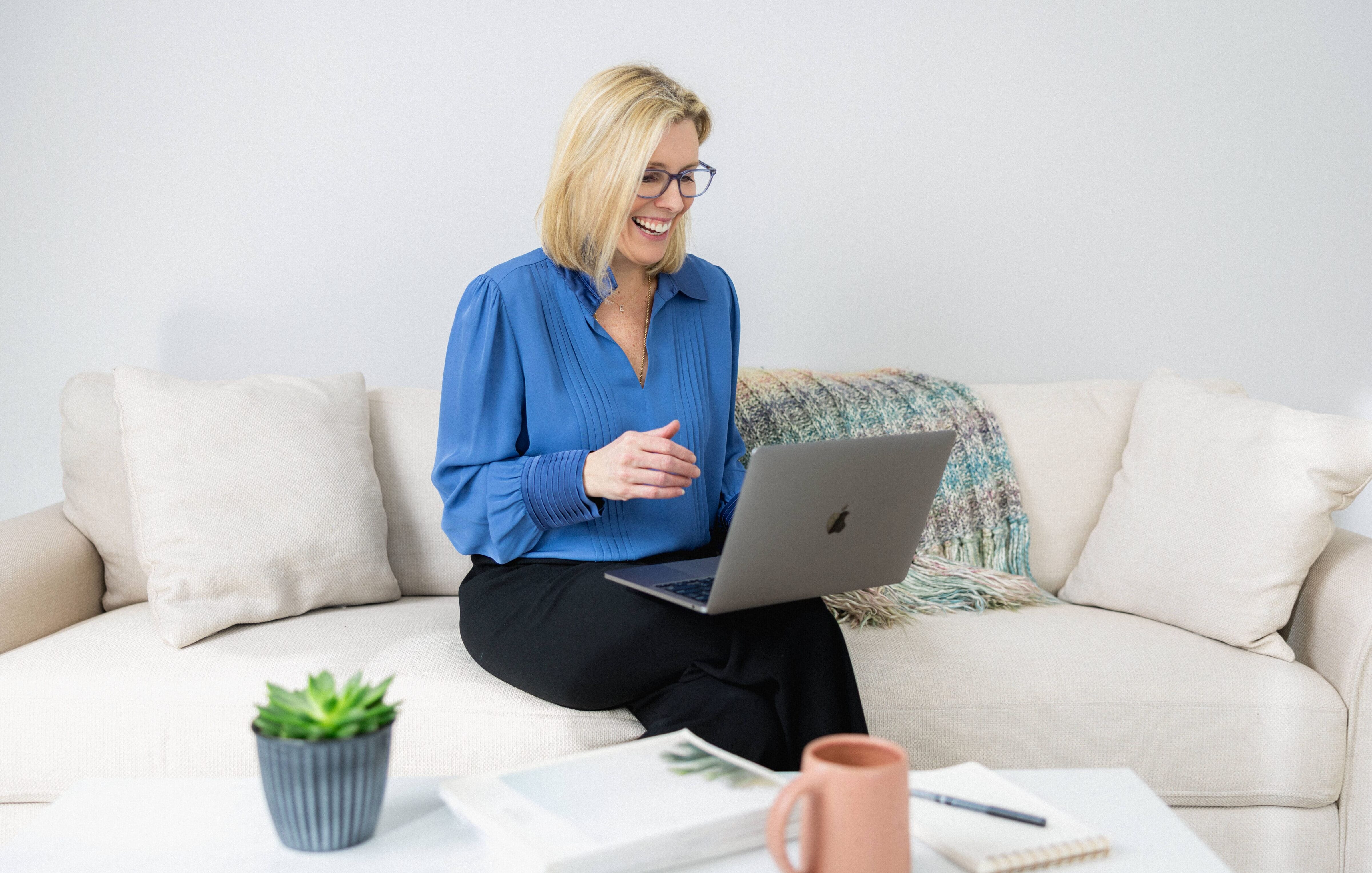 Elisabeth Tullis Schneider, LMFT, seated on a sofa with her laptop at The Stratara Group in Fairfield, CT