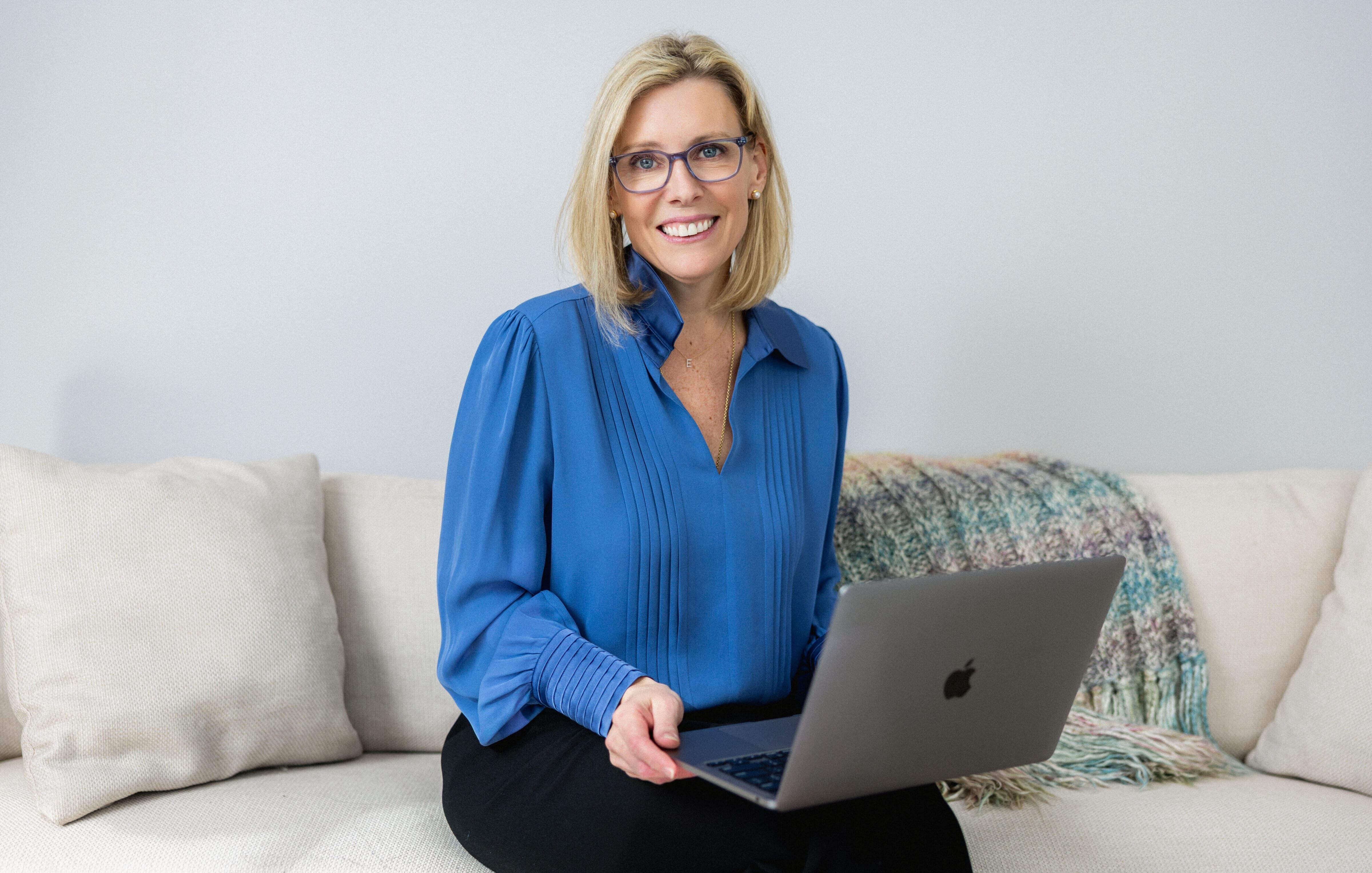 Elisabeth Tullis Schneider, LMFT, seated on a sofa with her laptop at The Stratara Group in Fairfield, CT