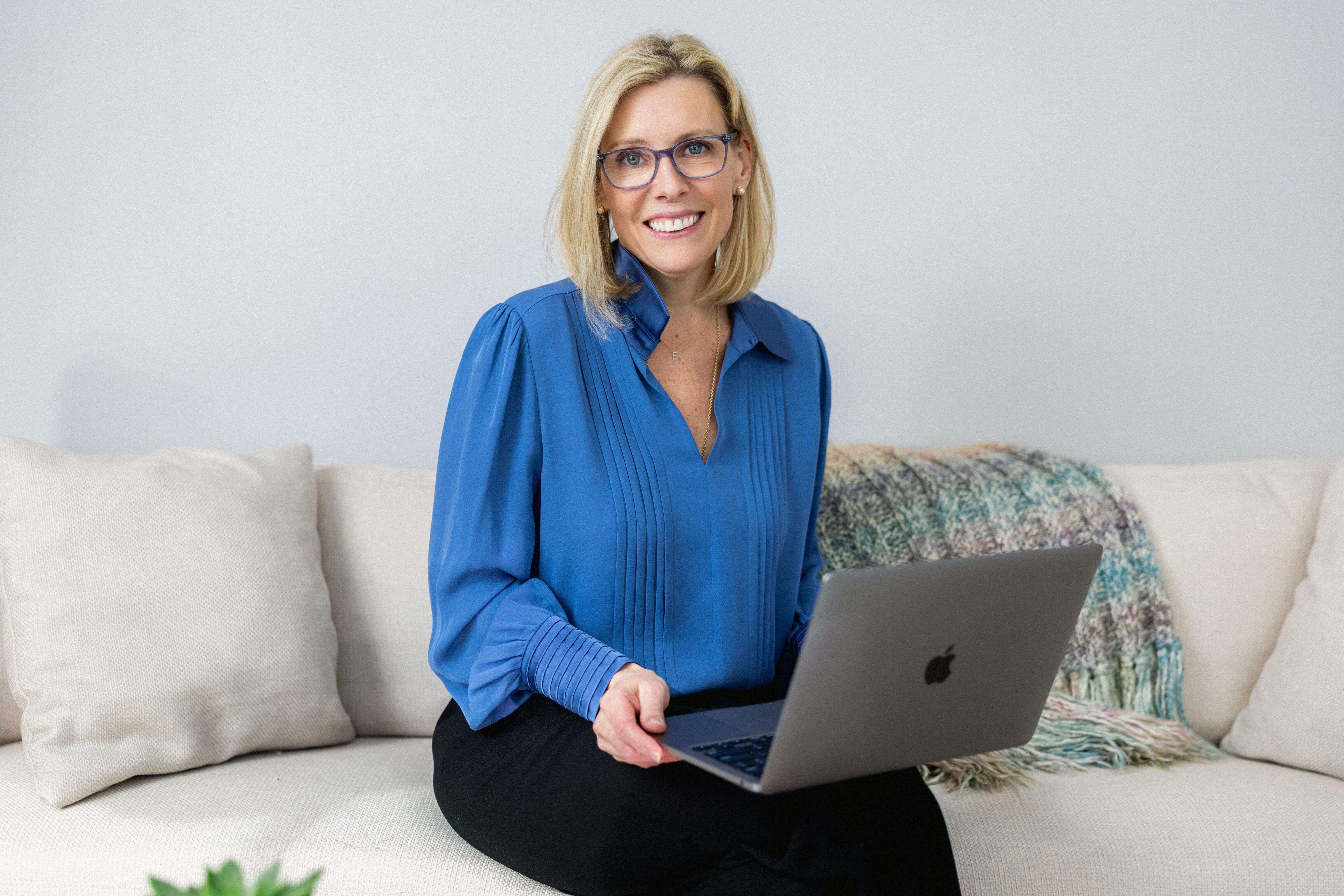 Elisabeth Tullis Schneider, LMFT, seated on a sofa with her laptop at The Stratara Group in Fairfield, CT