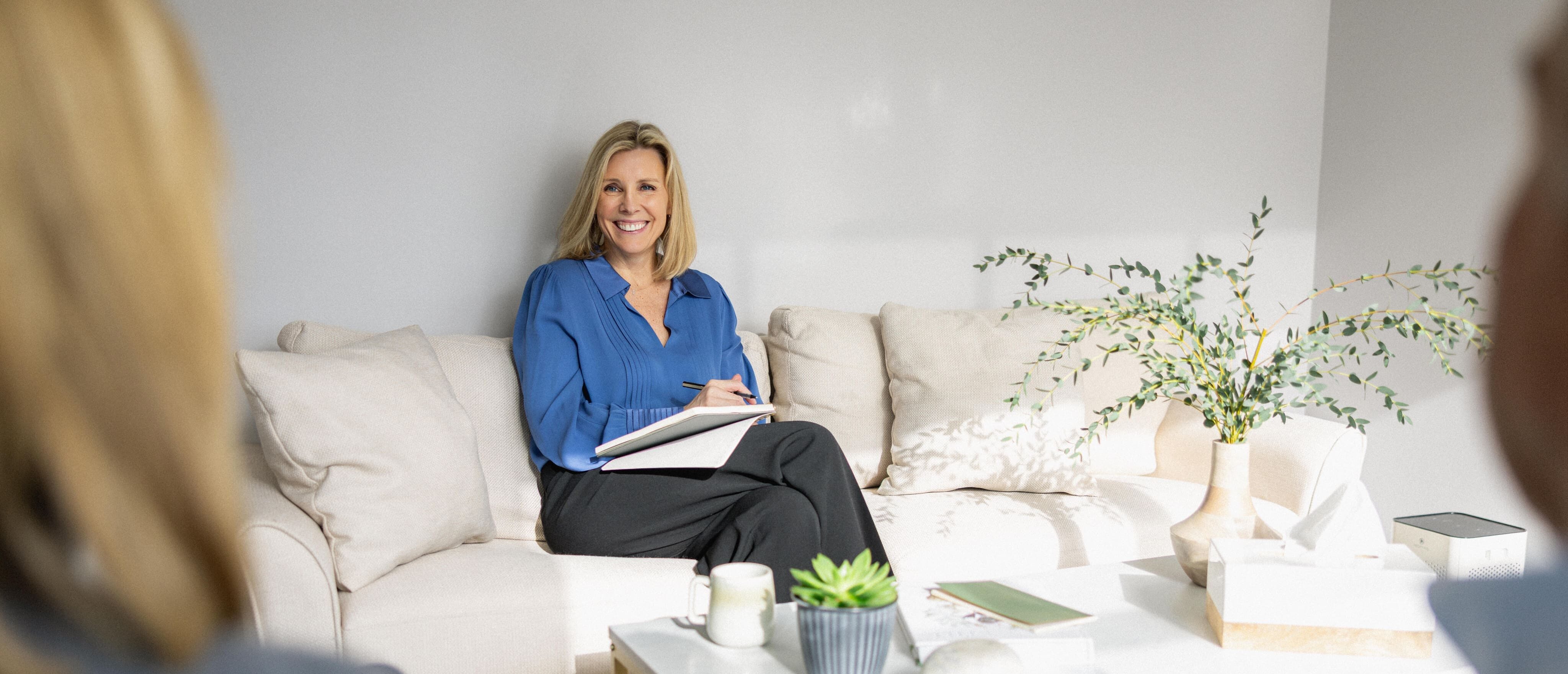Elisabeth Tullis Schneider seated on a sofa listening to clients during a session