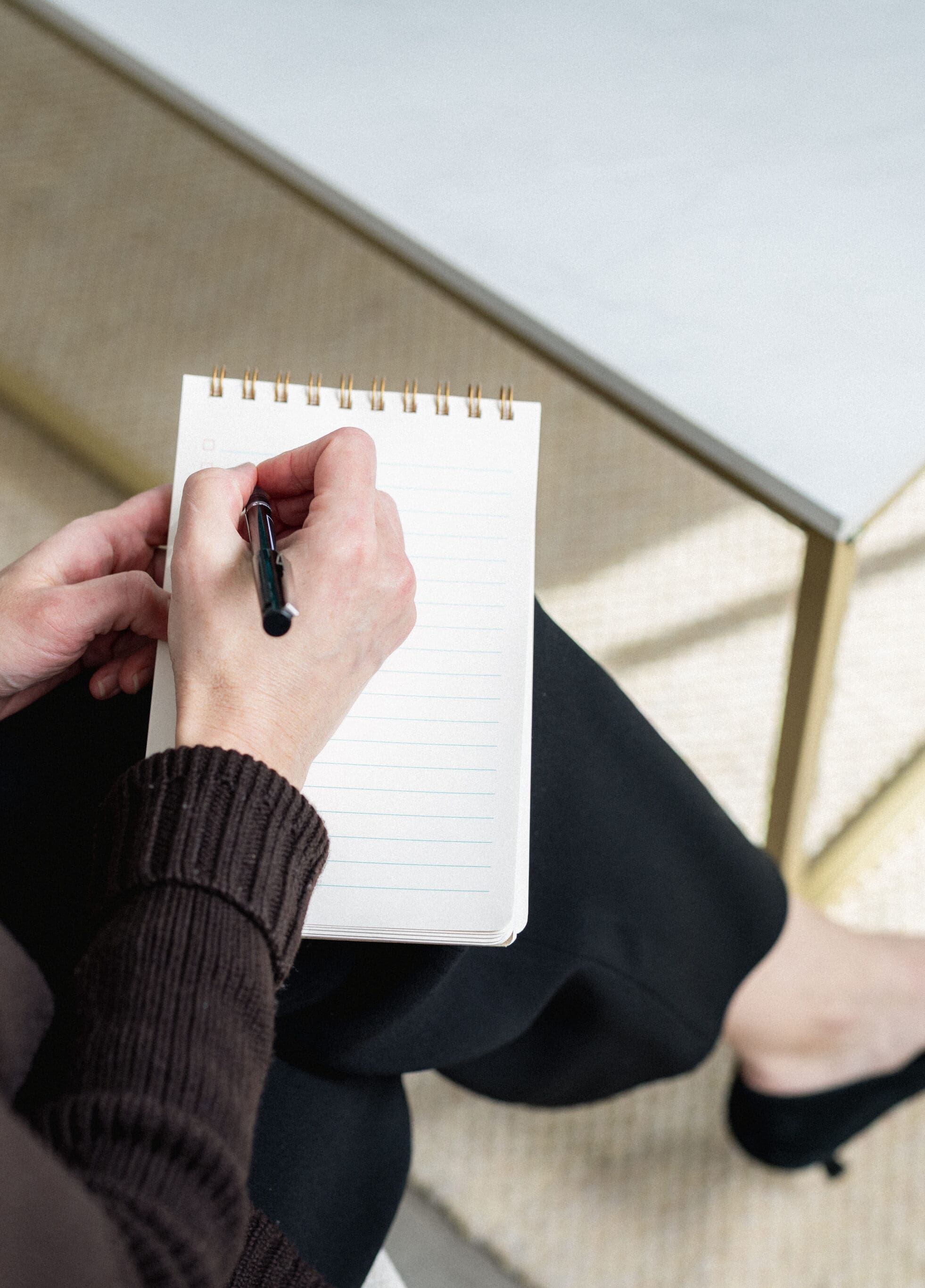 Close-up of a hand writing on a spiral notepad during a session